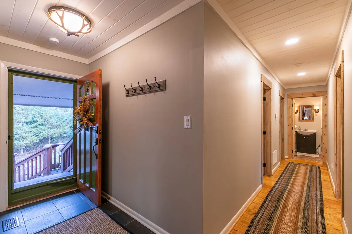 An entryway with a welcoming open door, rug, and coat hooks, evoking the first impressions of arriving at a warm, inviting home. The image suggests the ease of coming and going, which ties into exploring local attractions and returning to a cozy base.